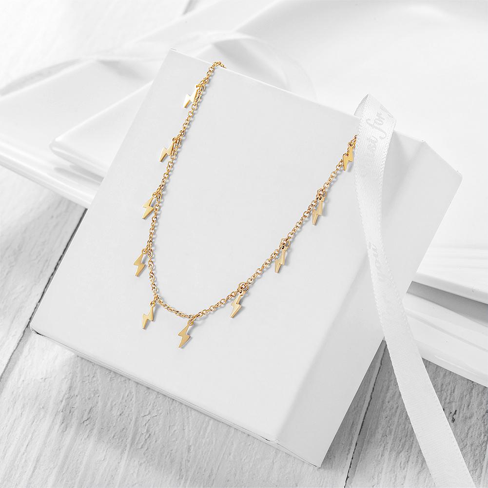 Delicate gold anklet with lightning charms displayed on white draped fabric – trendy ankle jewelry